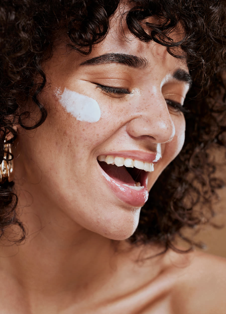 Mulher sorrindo com creme facial aplicado no rosto